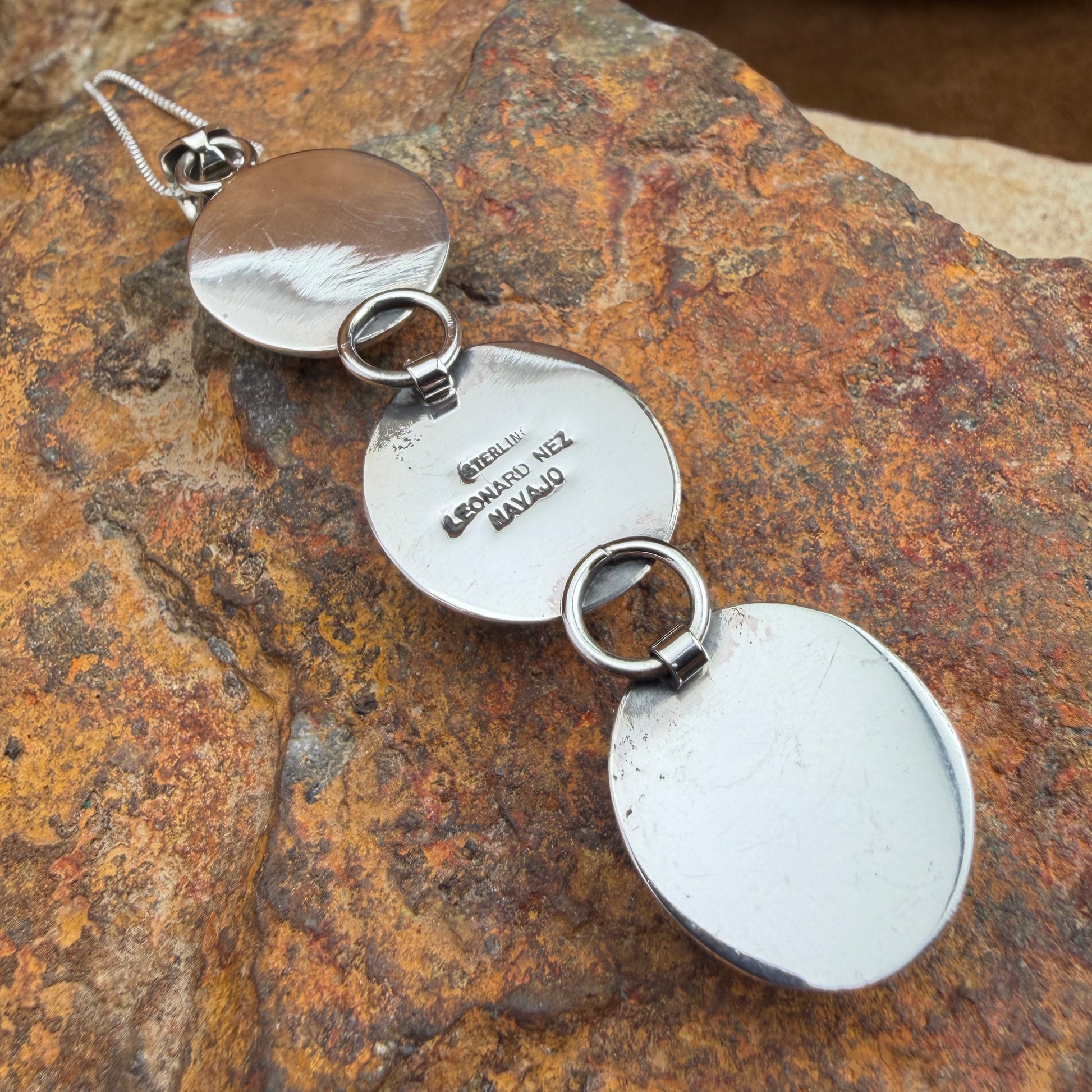 Back of a silver pendent stamped with LEONARD NEZ, STERLING, NAVAJO 