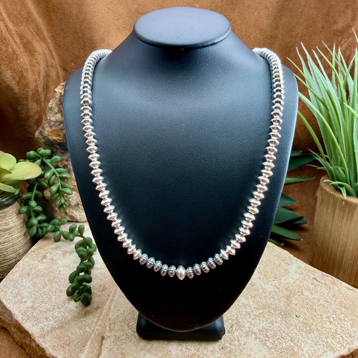 Polished sterling silver beaded necklace on a black mannequin neck 