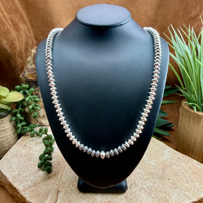 Polished sterling silver beaded necklace on a black mannequin neck 