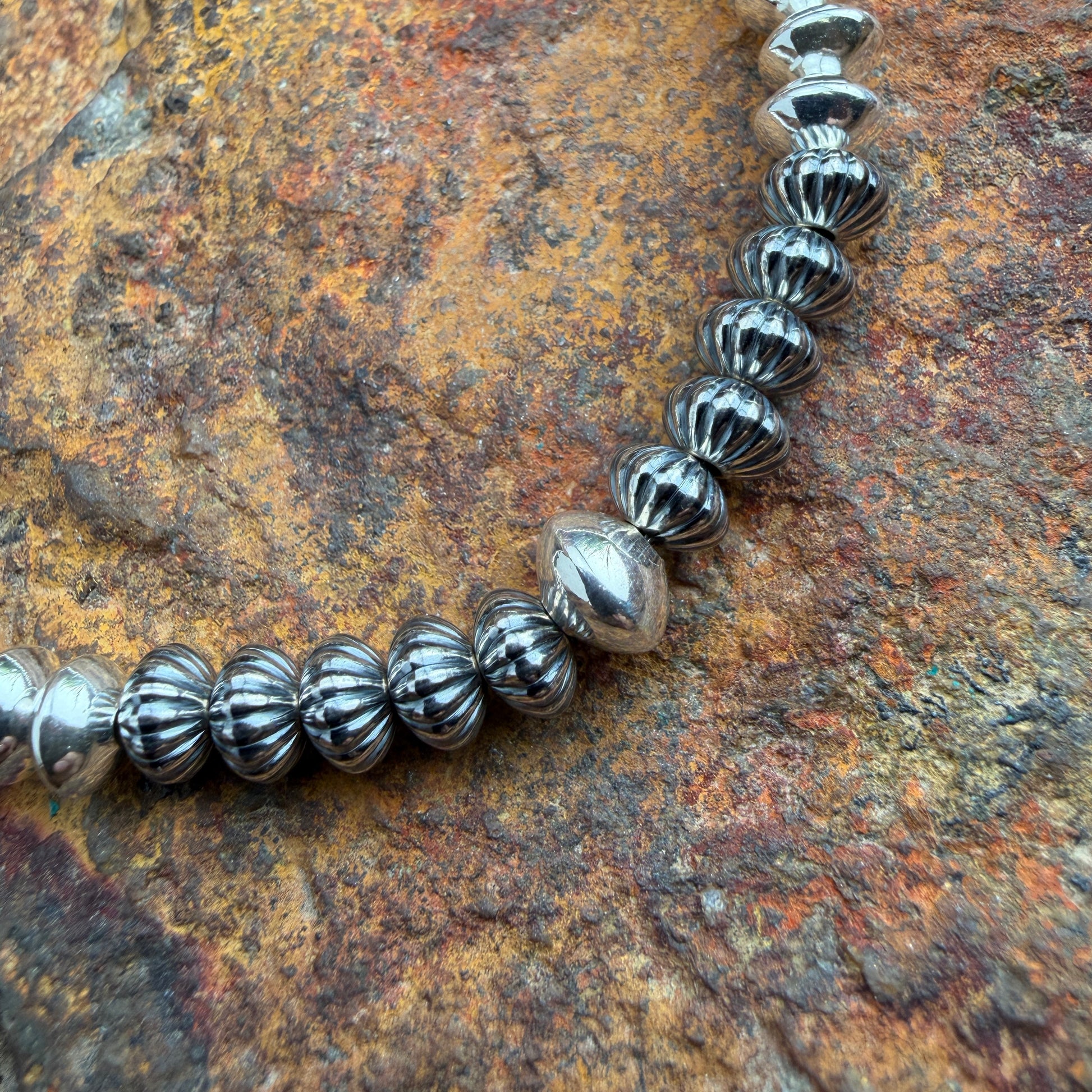 close up shot of beads on necklace, features a melon ridge design on oxidized beads with one larger center bead in the middle