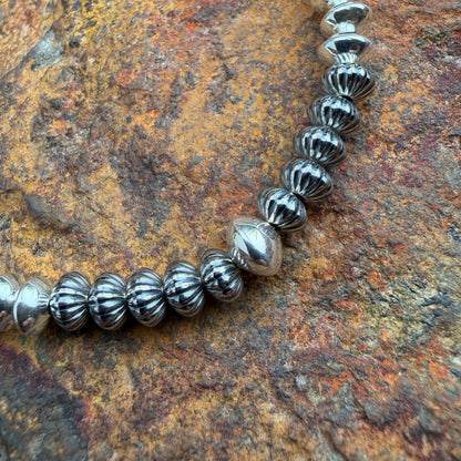 close up shot of beads on necklace, features a melon ridge design on oxidized beads with one larger center bead in the middle