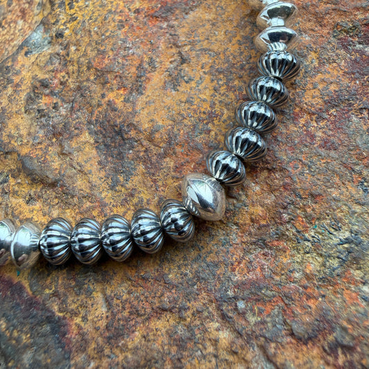 close up shot of beads on necklace, features a melon ridge design on oxidized beads with one larger center bead in the middle