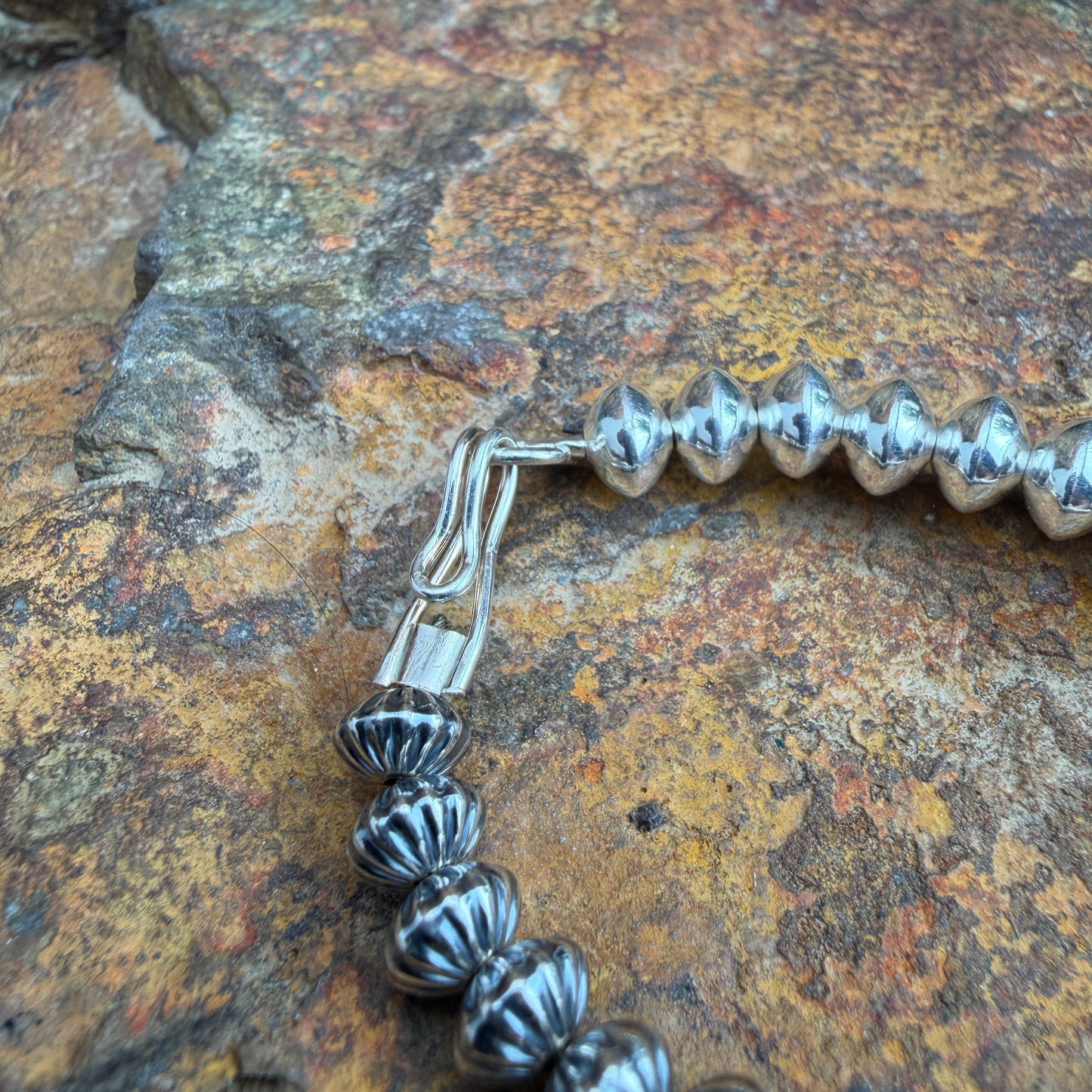 showcases a hook and eye clasp on a silver beaded necklace