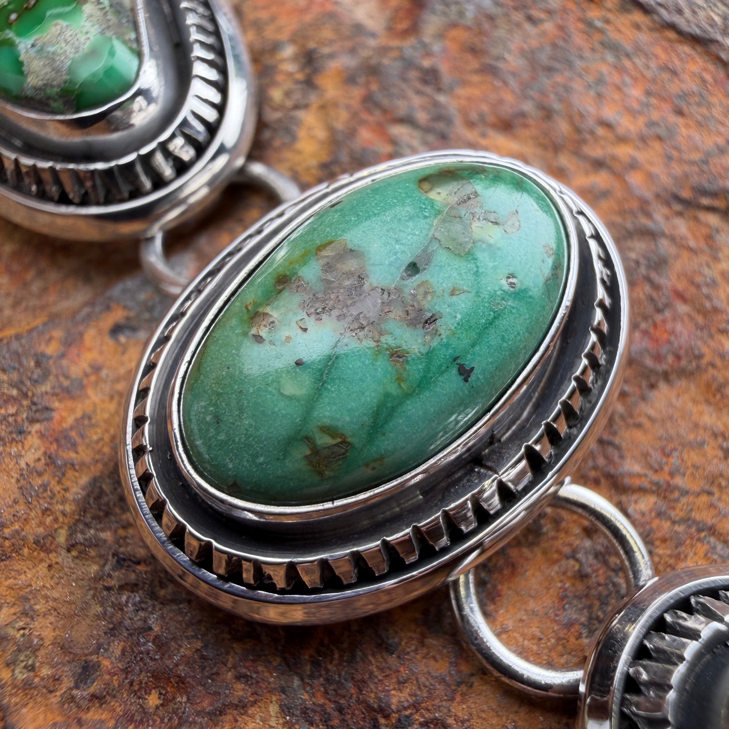 Turquoise stone with silver band on a textured surface