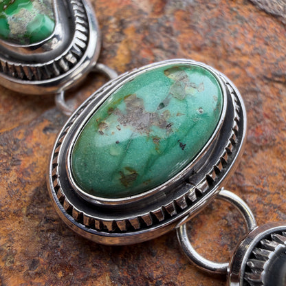 Turquoise stone with silver band on a textured surface