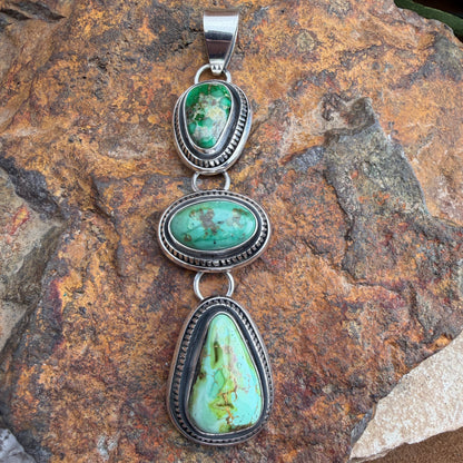 Turquoise pendant with silver setting on a stone background