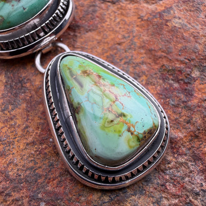 Turquoise stone pendant with silver setting on a textured brown surface