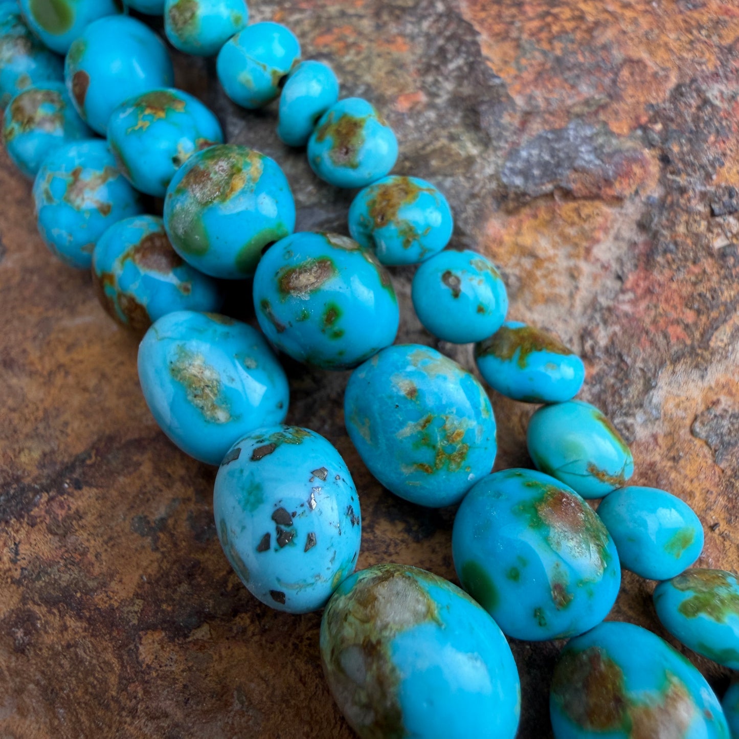 Turquoise beads with brown speckles on a textured stone surface