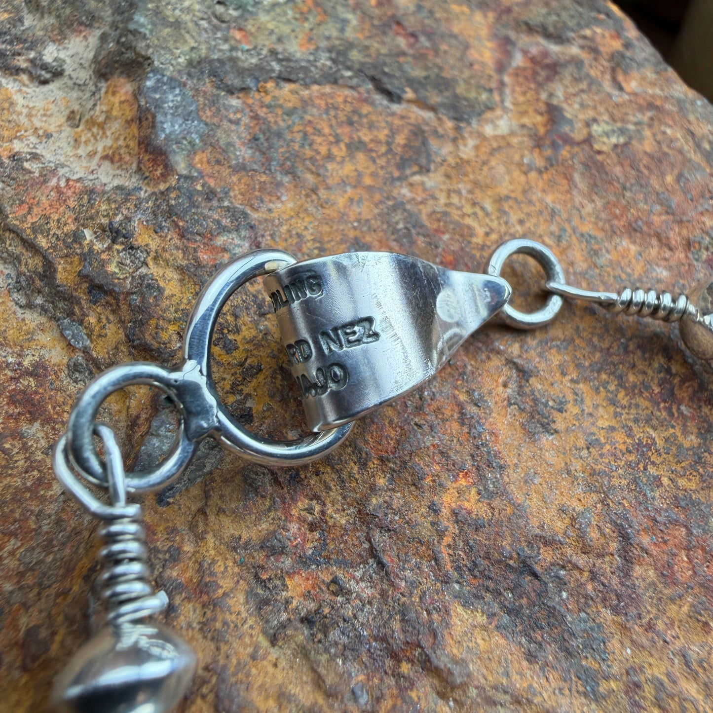 Close up of eye and hook clasp, stamped LEONARD NEZ, STERLING, and NAVAJO