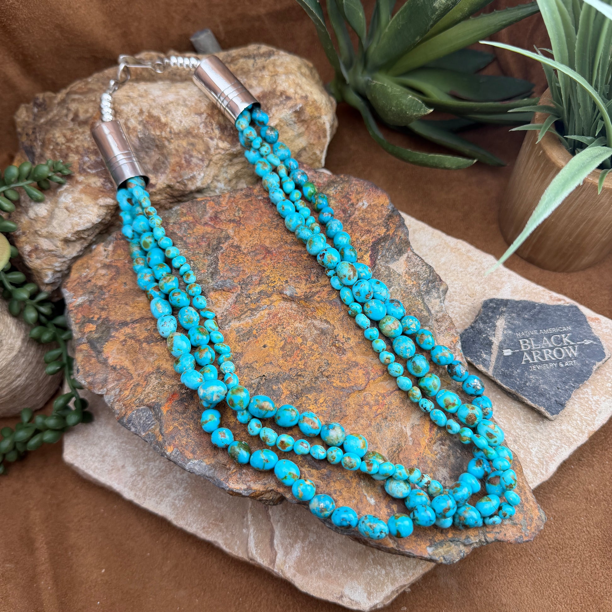 Turquoise beaded necklace on a stone surface with plants in the background