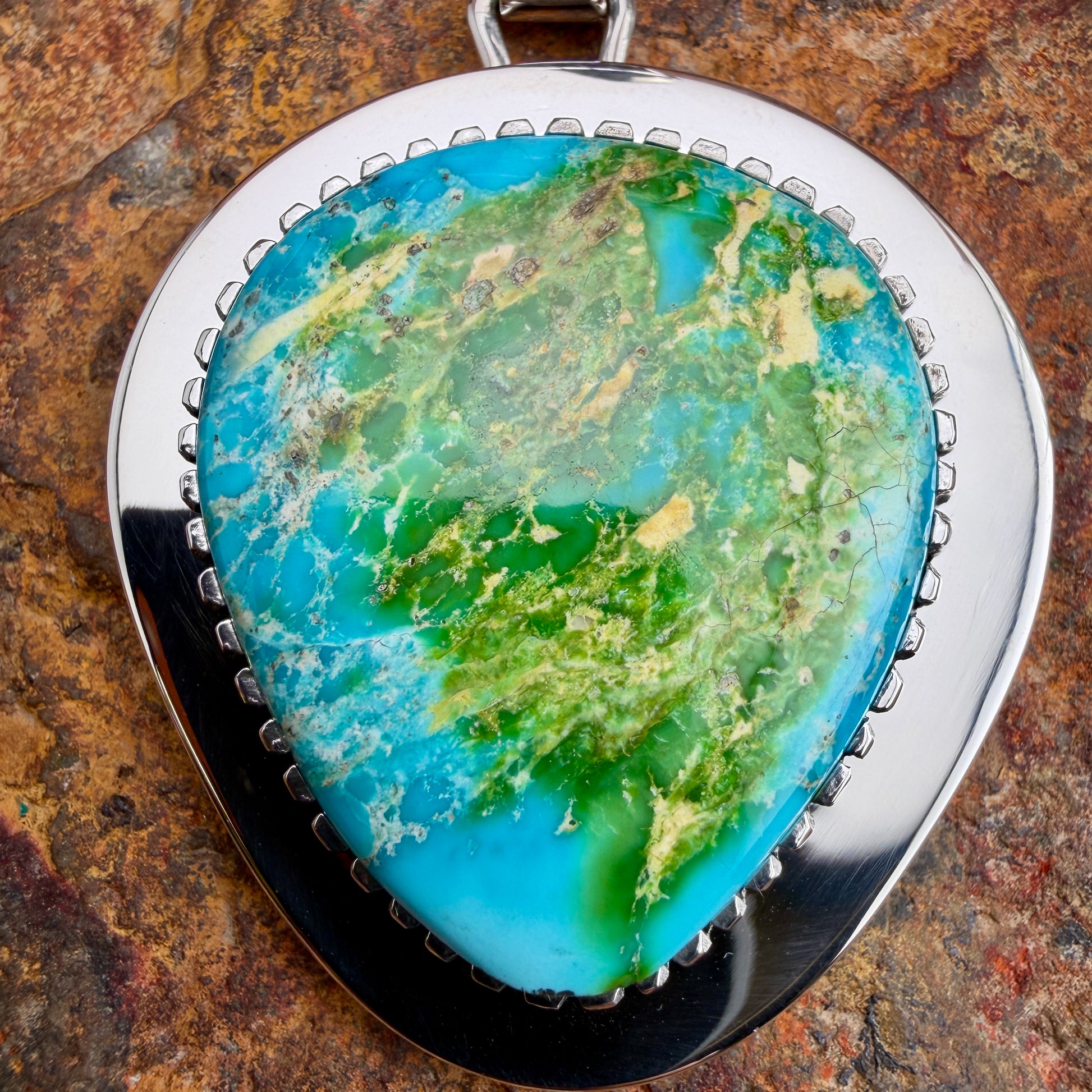 Pendant with a green and blue stone on a brown stone background