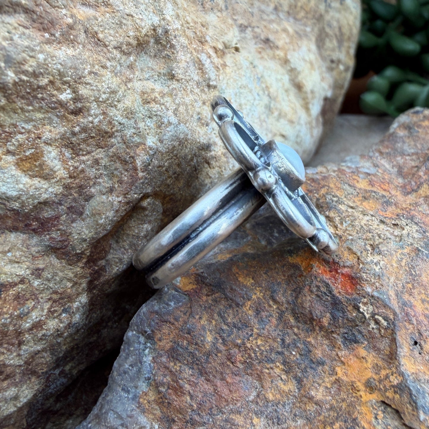 Silver flower shaped ring on a textured stone surface