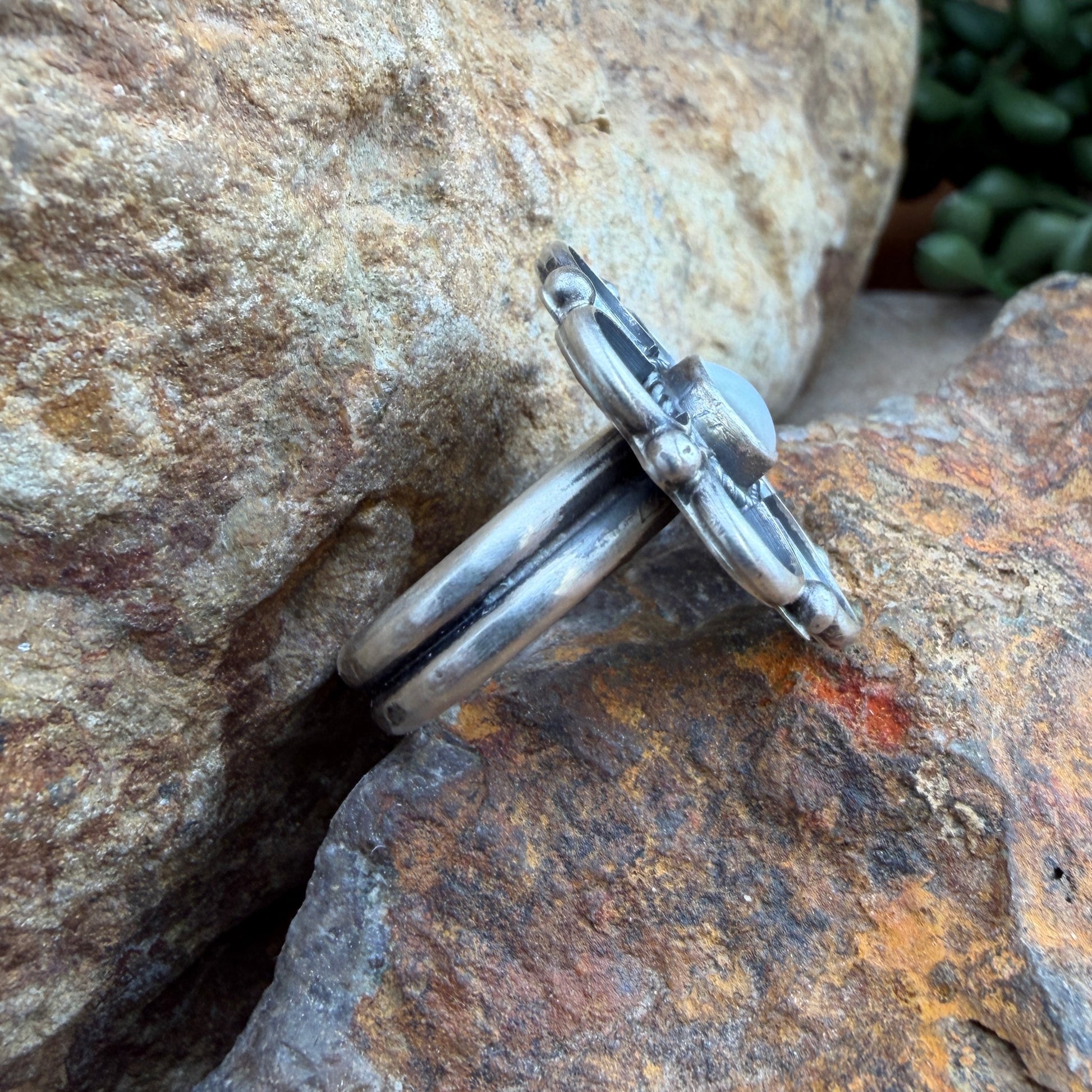 Silver flower shaped ring on a textured stone surface