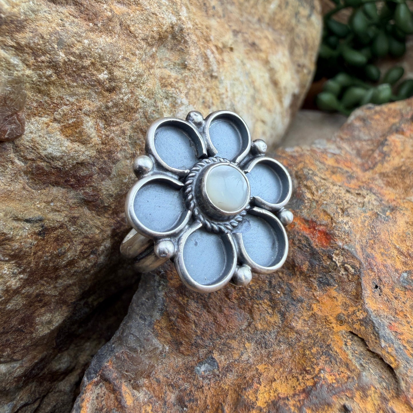Silver ring with a floral design on a stone surface