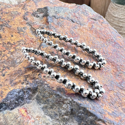 Silver beaded earrings on a textured stone surface