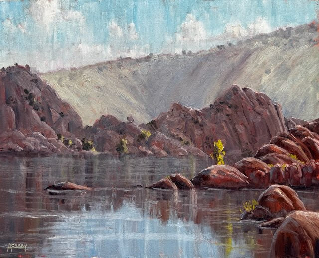 An oil painting of a scenic landscape featuring reddish-brown rocky cliffs and boulders reflected in calm water under a blue sky with white clouds.