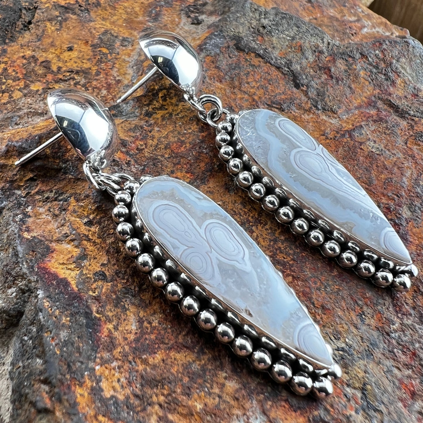 Silver and stone earrings on a textured stone surface