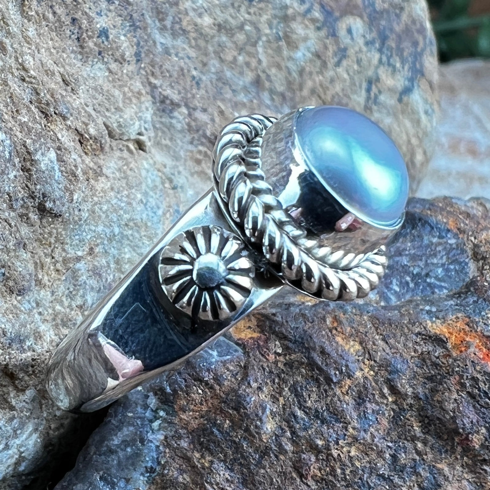 Silver ring with a grey stone on a rocky surface