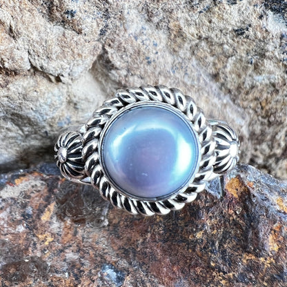 Silver ring with a grey gemstone on a rocky surface
