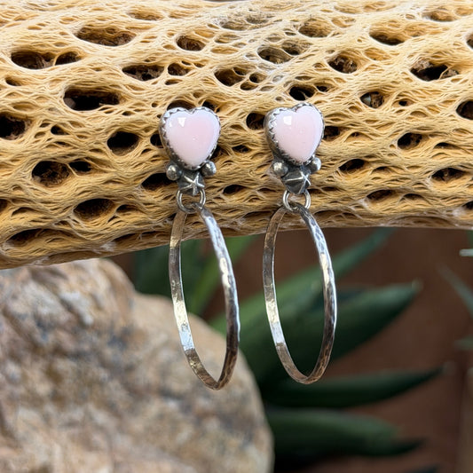 Angled view of pink conch heart earrings with scalloped bezel settings