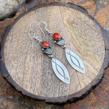 Angled view of red coral scalloped bezel earrings and geometric silver drops