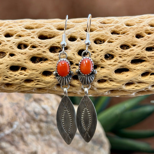Sterling silver geometric dangles beneath oval red coral stones