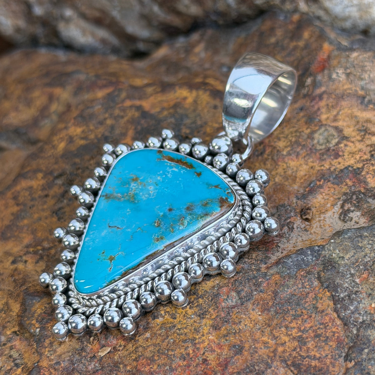Angled view of large Royston turquoise pendant by Artie Yellowhorse