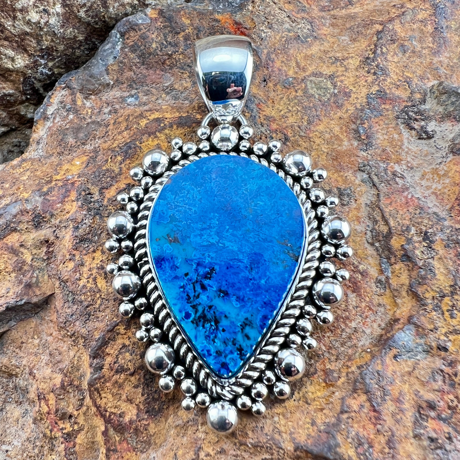 Blue pendant with silver border on a stone background