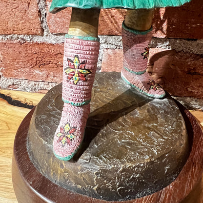 Person wearing pink beaded boots with butterfly designs on a stone surface.
