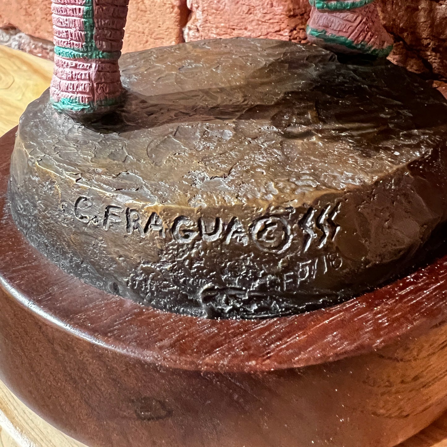 Close-up of a stone object with 'C. FRAGUA' branding on a wooden base.