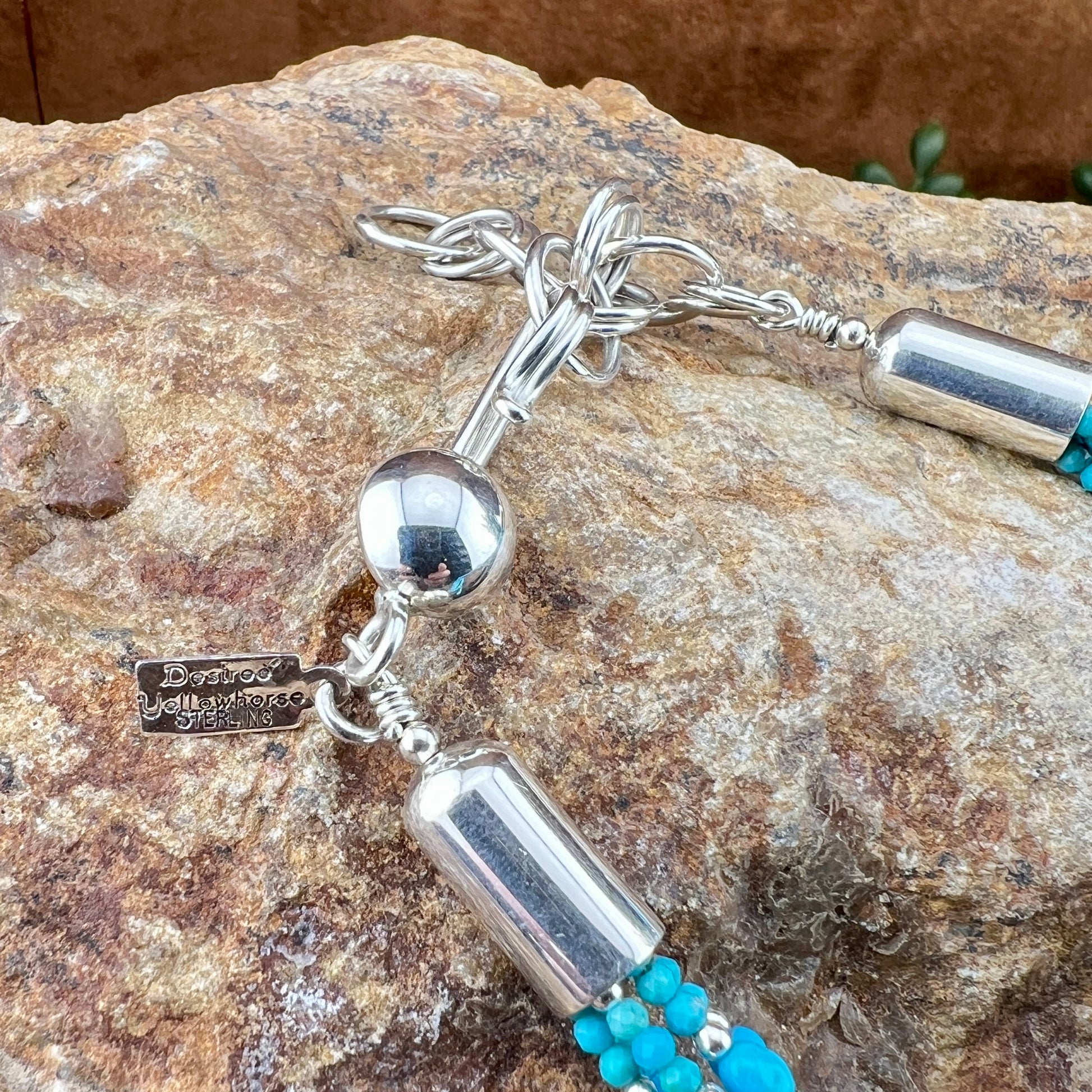 Silver and turquoise beaded necklace on a stone surface