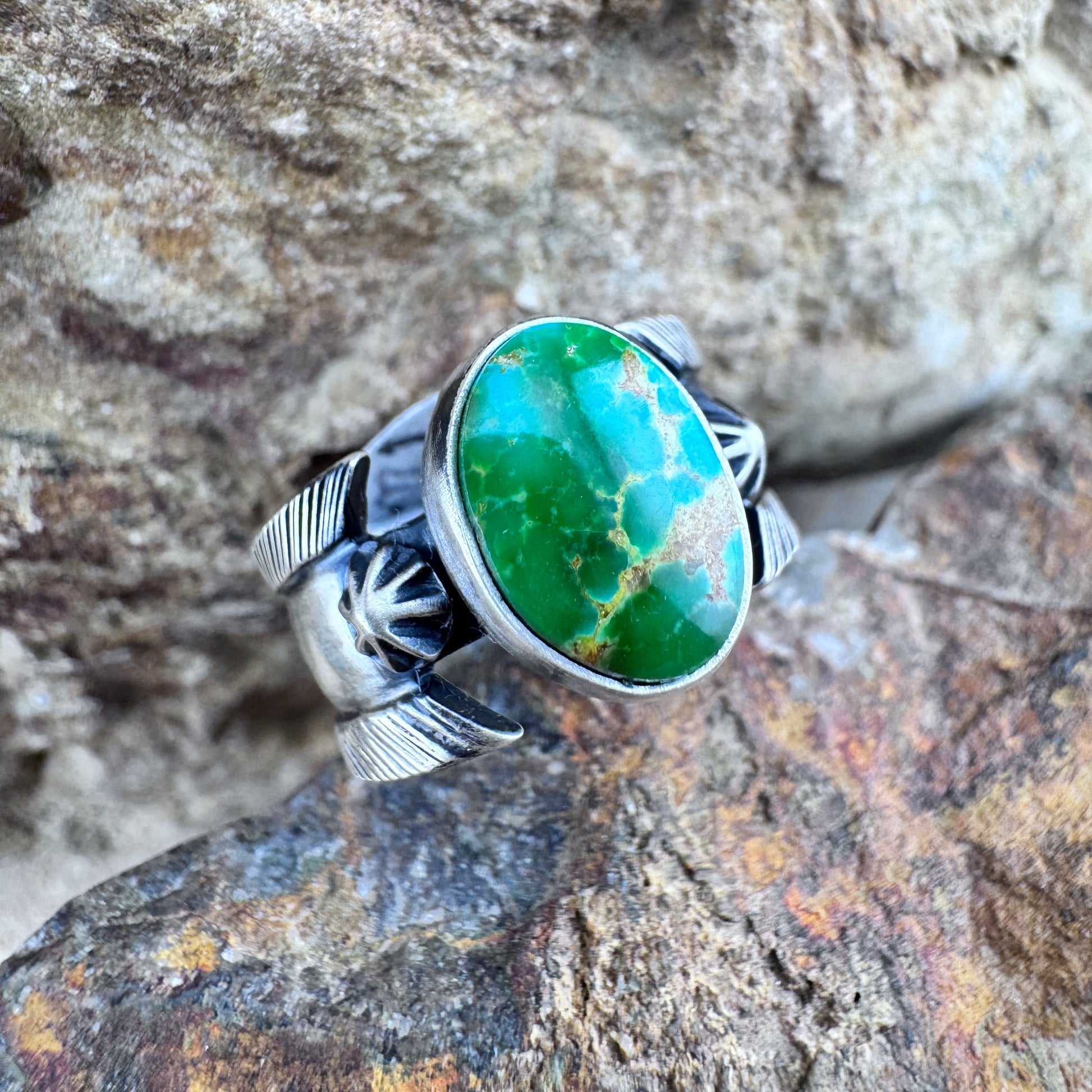 Silver ring with a green stone on a rocky background