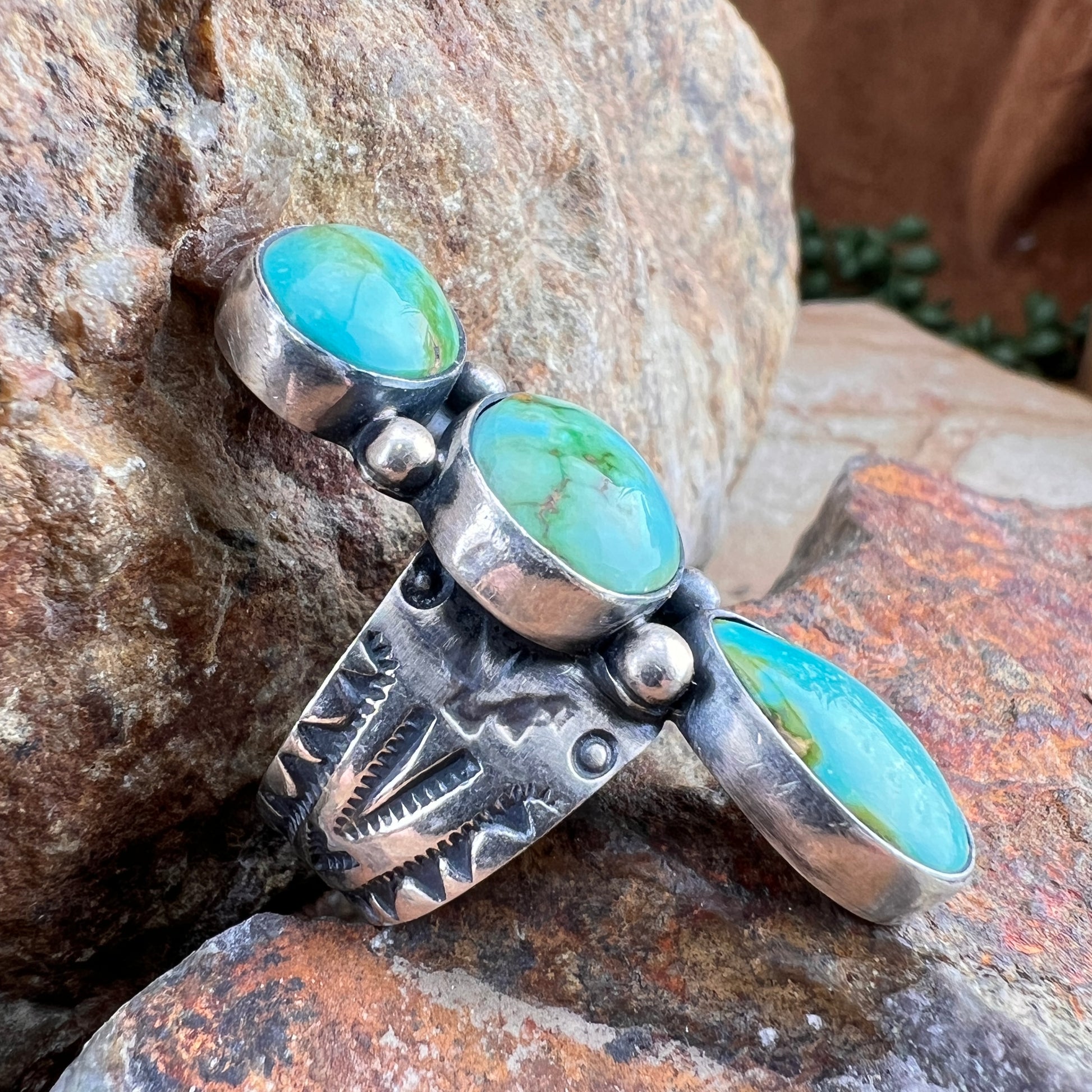 Silver ring with turquoise stones on a stone surface