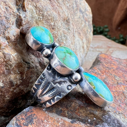 Silver ring with turquoise stones on a stone surface