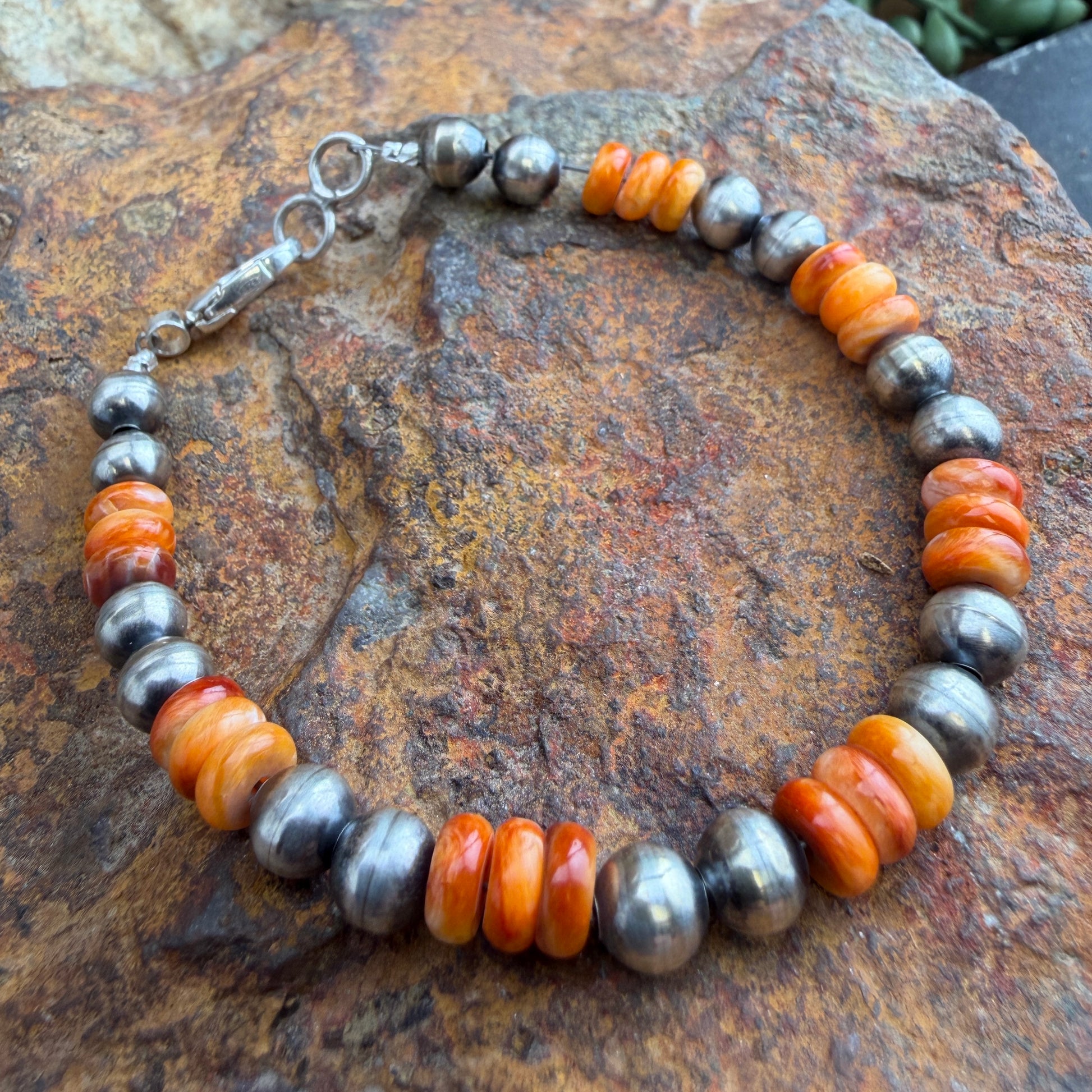 Bracelet with orange and silver beads on a stone surface