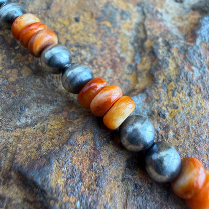 Beaded bracelet with orange and gray beads on a textured surface
