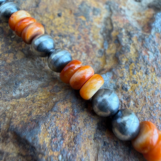Beaded bracelet with orange and gray beads on a textured surface