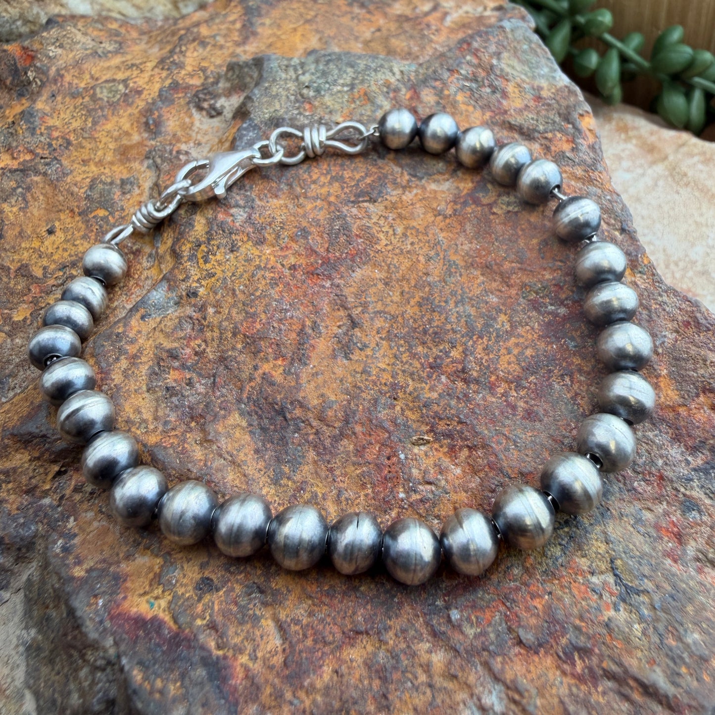 Silver beaded bracelet on a textured stone surface
