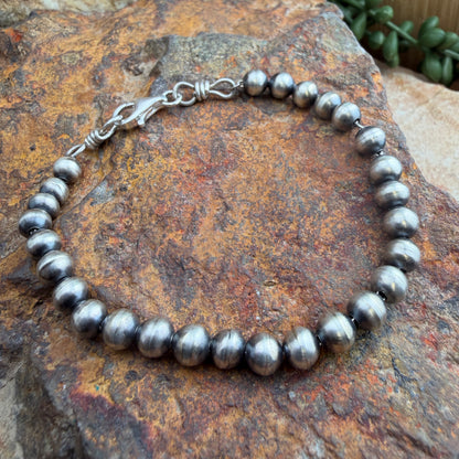Silver beaded bracelet on a textured stone surface