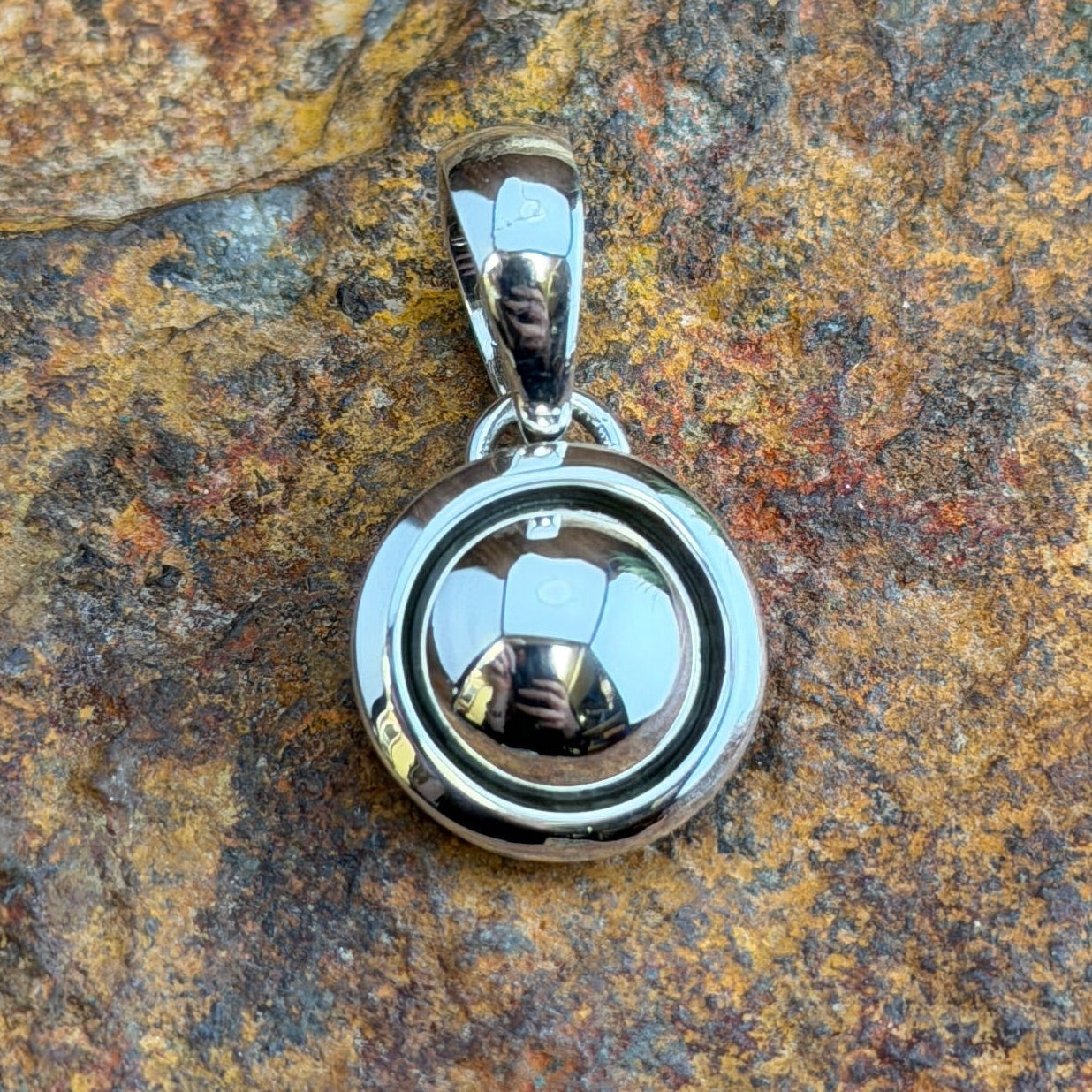  A small Pendant. A polished sterling silver dome sits nestled within a smooth shadowbox rim, creating a clean, sculptural depth in a petite, wearable form. Simple loop bail. 