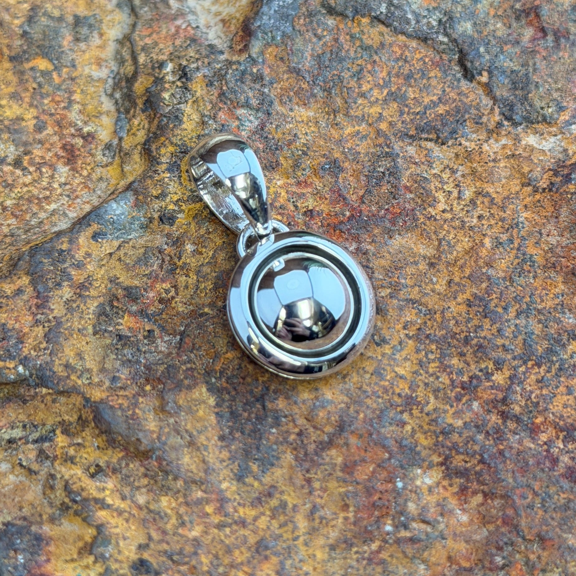  A small Pendant. A polished sterling silver dome sits nestled within a smooth shadowbox rim, creating a clean, sculptural depth in a petite, wearable form. Simple loop bail. 