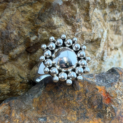 A polished sterling silver dome rises from the center, encircled by two concentric rings of hand-soldered silver shot beads radiating outward in a sunburst pattern.