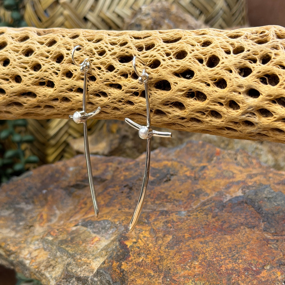 silver crossing earrings with pearl hanging from cactus spine with rocks in background