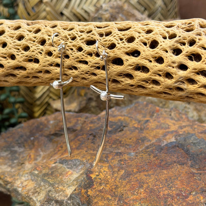 silver crossing earrings with pearl hanging from cactus spine with rocks in background