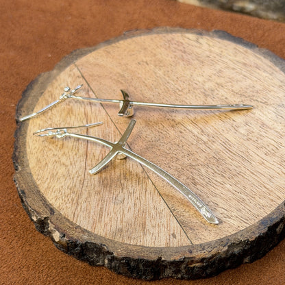 silver cross earrings displayed on wood