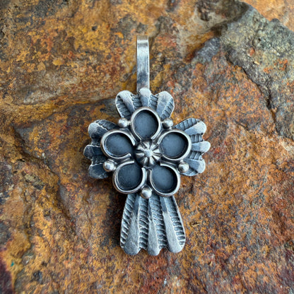 Silver floral cross pendant on a textured stone background