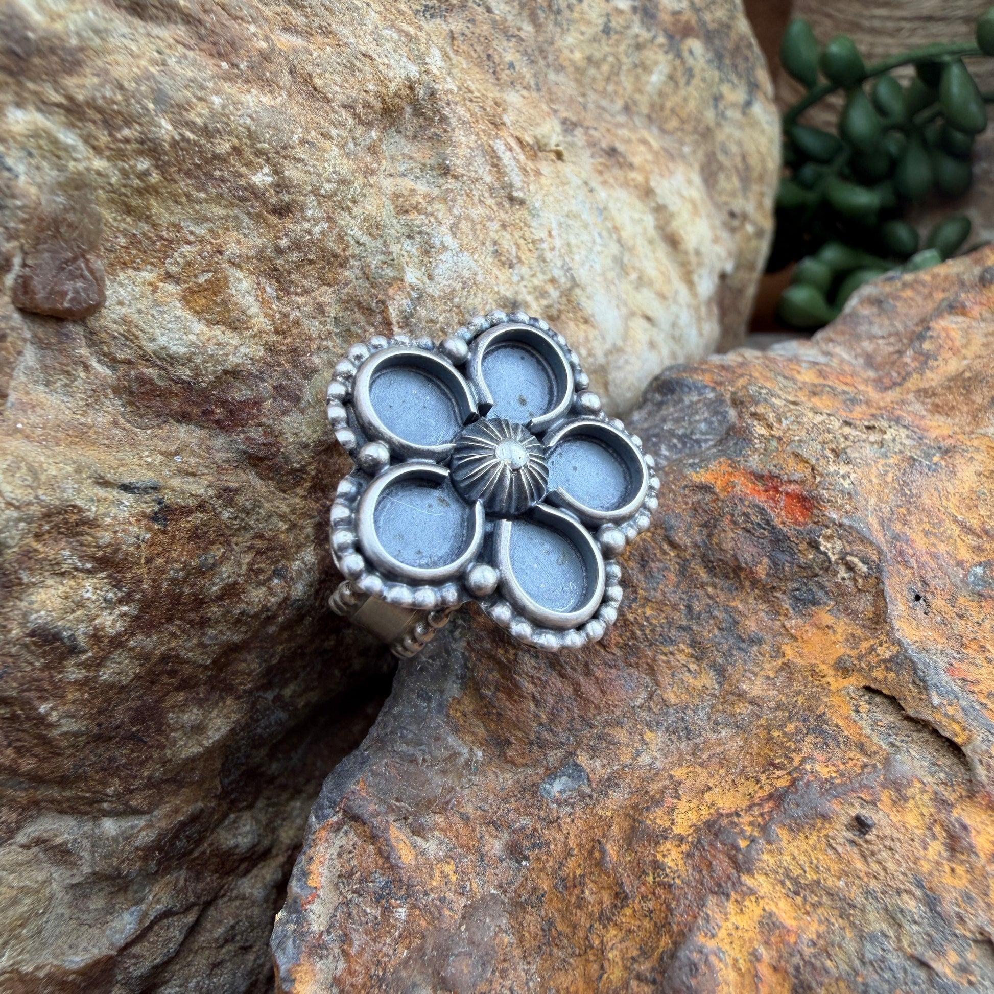 Silver floral ring  on a textured stone surface