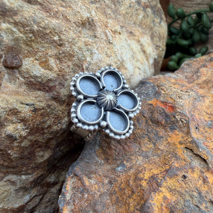 Silver floral ring  on a textured stone surface