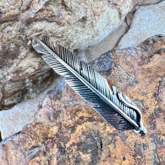 Silver feather-shaped object on a rocky surface