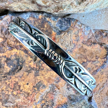 Silver feather design on a stone background